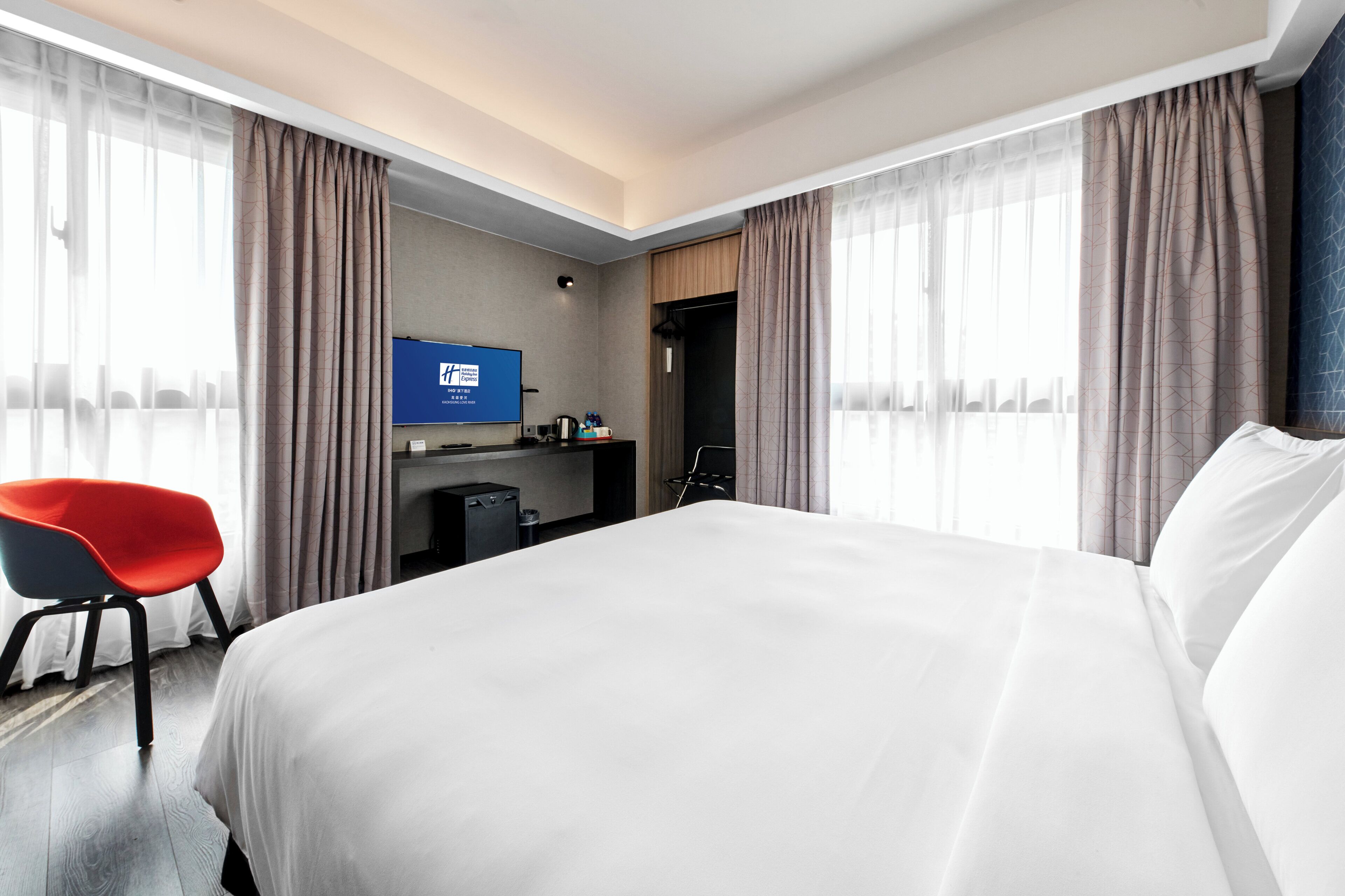 A hotel room with a bed, a desk, a chair, and a television.