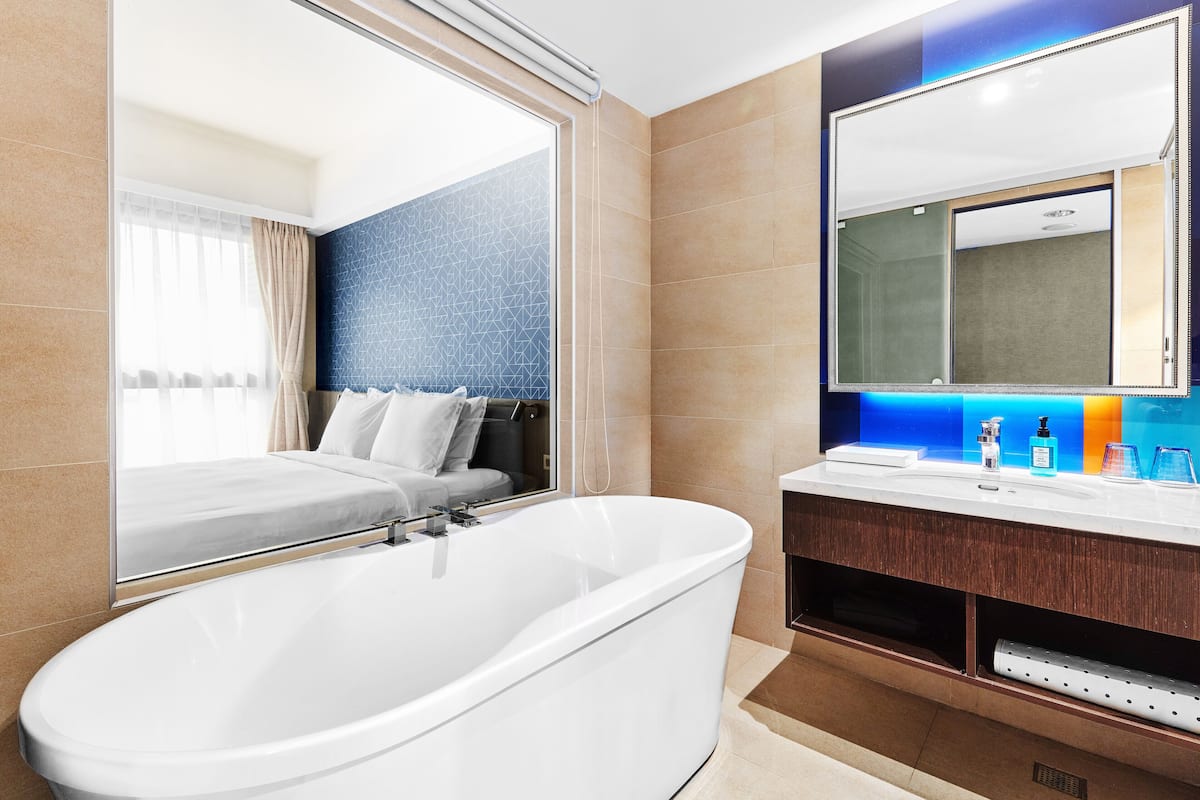 Un baño moderno con una bañera independiente, un espejo grande y un tocador con lavabo y artículos de aseo.