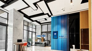 Een moderne lobby met een receptiebalie, een zithoek en een blauwe accentmuur.