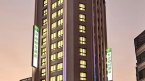 Een hoog hotelgebouw met meerdere verdiepingen, verlichte ramen en groene signalering die aangeeft dat het een Holiday Inn Express is.