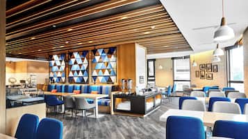 A modern restaurant with wooden ceiling panels, blue and grey seating, and a buffet area.