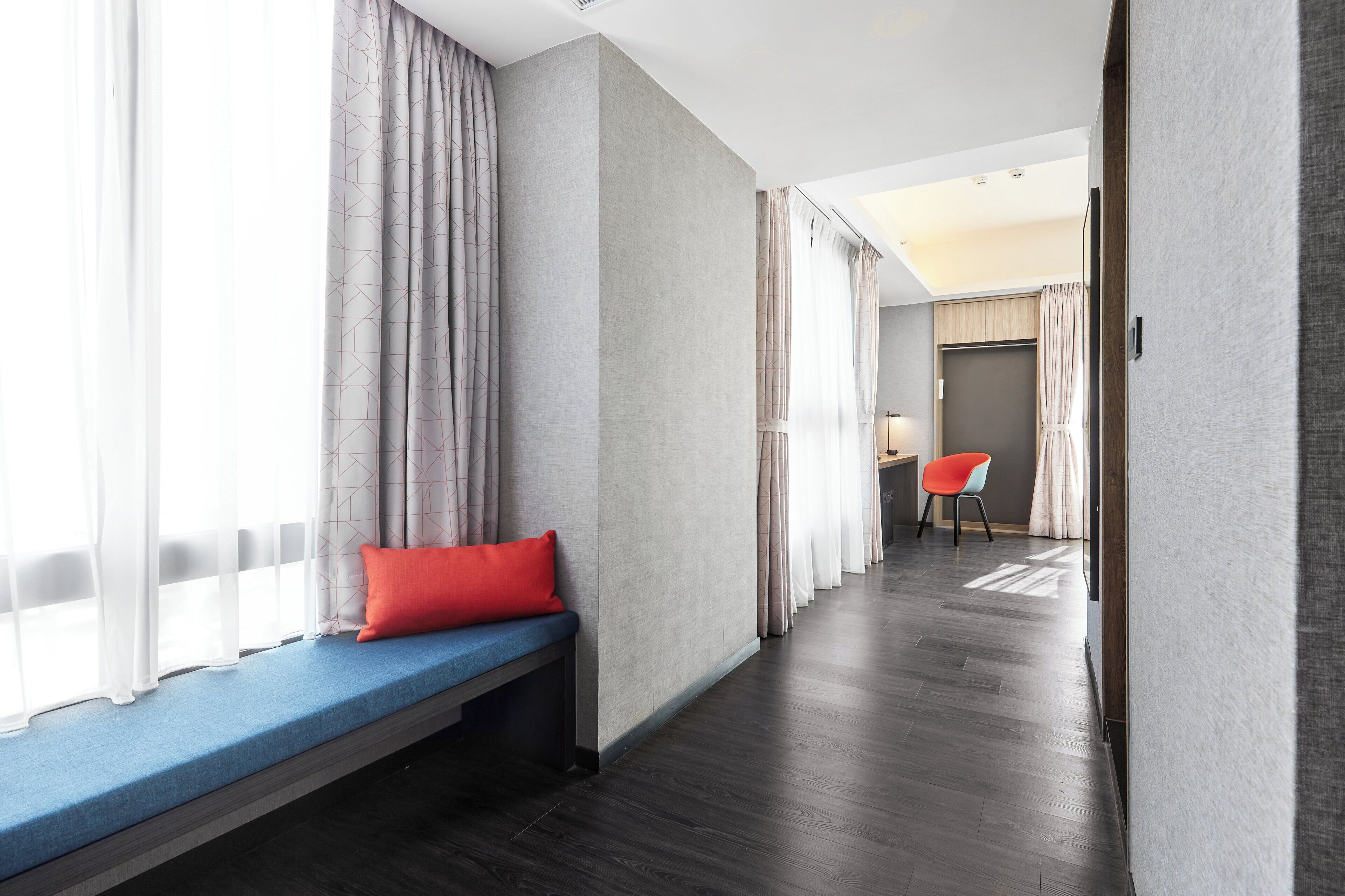 A hotel room with a bench, a desk, and a chair.