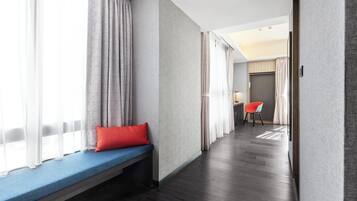 A hotel room with a bench, a desk, and a chair.