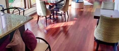 Un comedor amplio con suelo de madera y ventanas grandes.