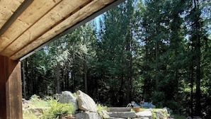 A stone staircase leading up to a wooden structure with a view of a forested area. - Davis Brook Retreat (Sechelt)
