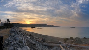 A coastal view with a wooden pier extending into calm waters, a clear sky, and distant landforms. - Davis Brook Retreat (Sechelt)