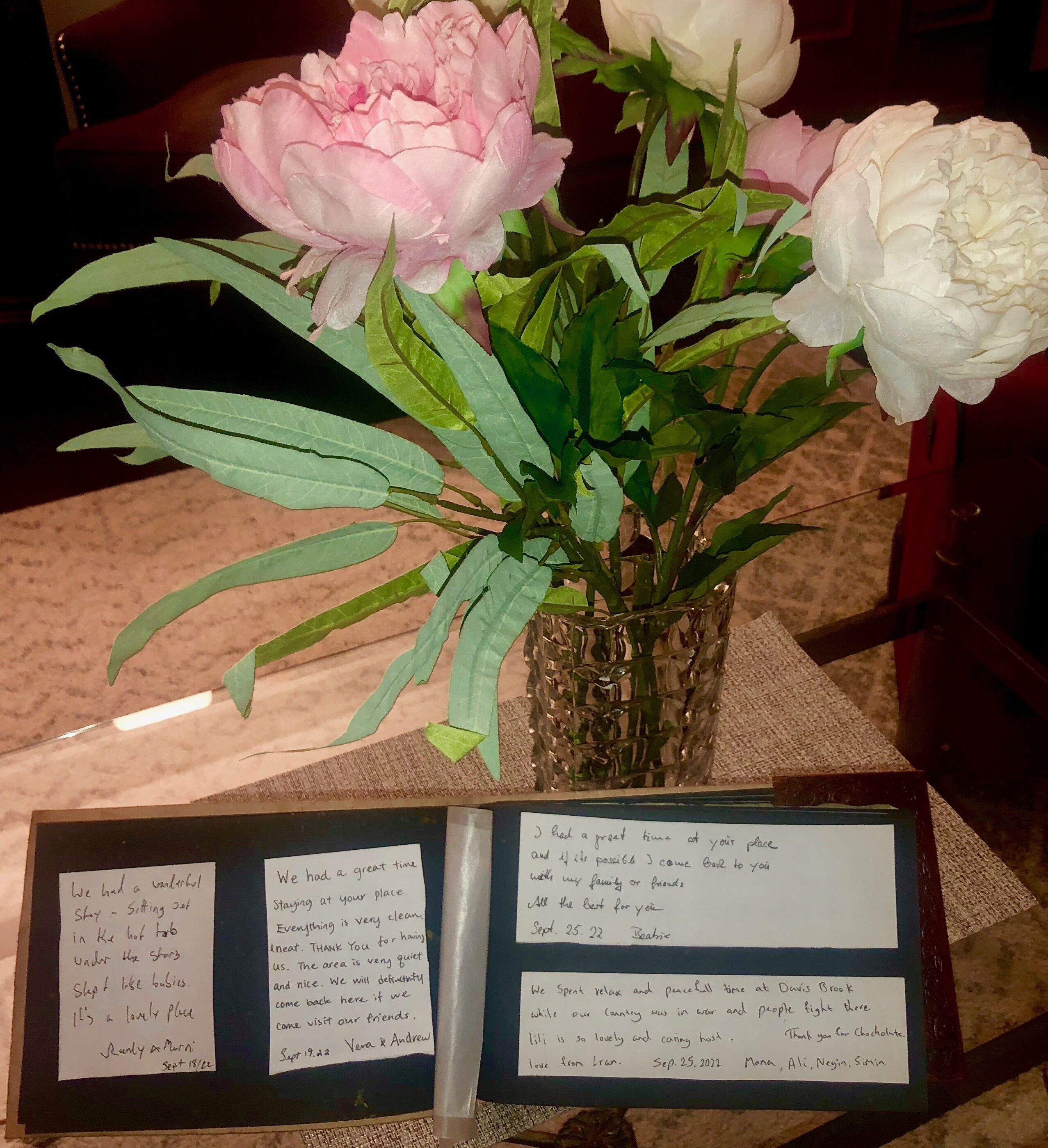 A vase with pink and white flowers on a table with handwritten notes.