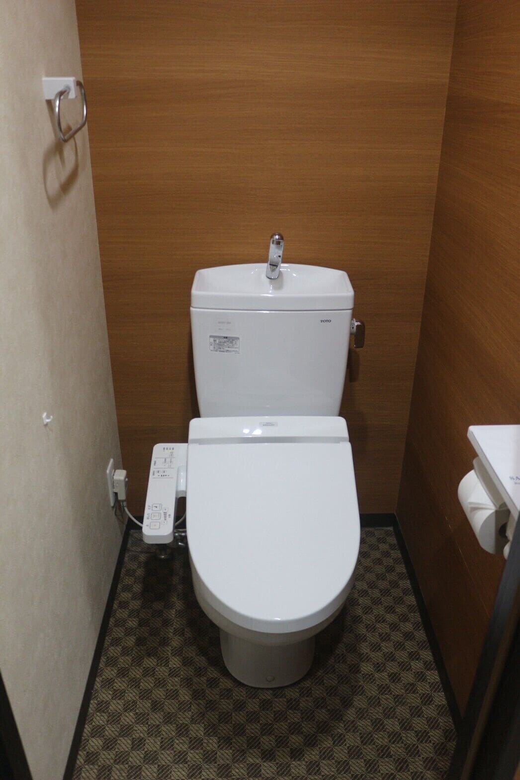 Ein kleines, kompaktes Badezimmer mit Toilette und einem Wandwaschbecken.