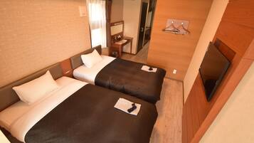 Quarto de hotel com duas camas, uma mesinha, uma cadeira, televisão e espelho.