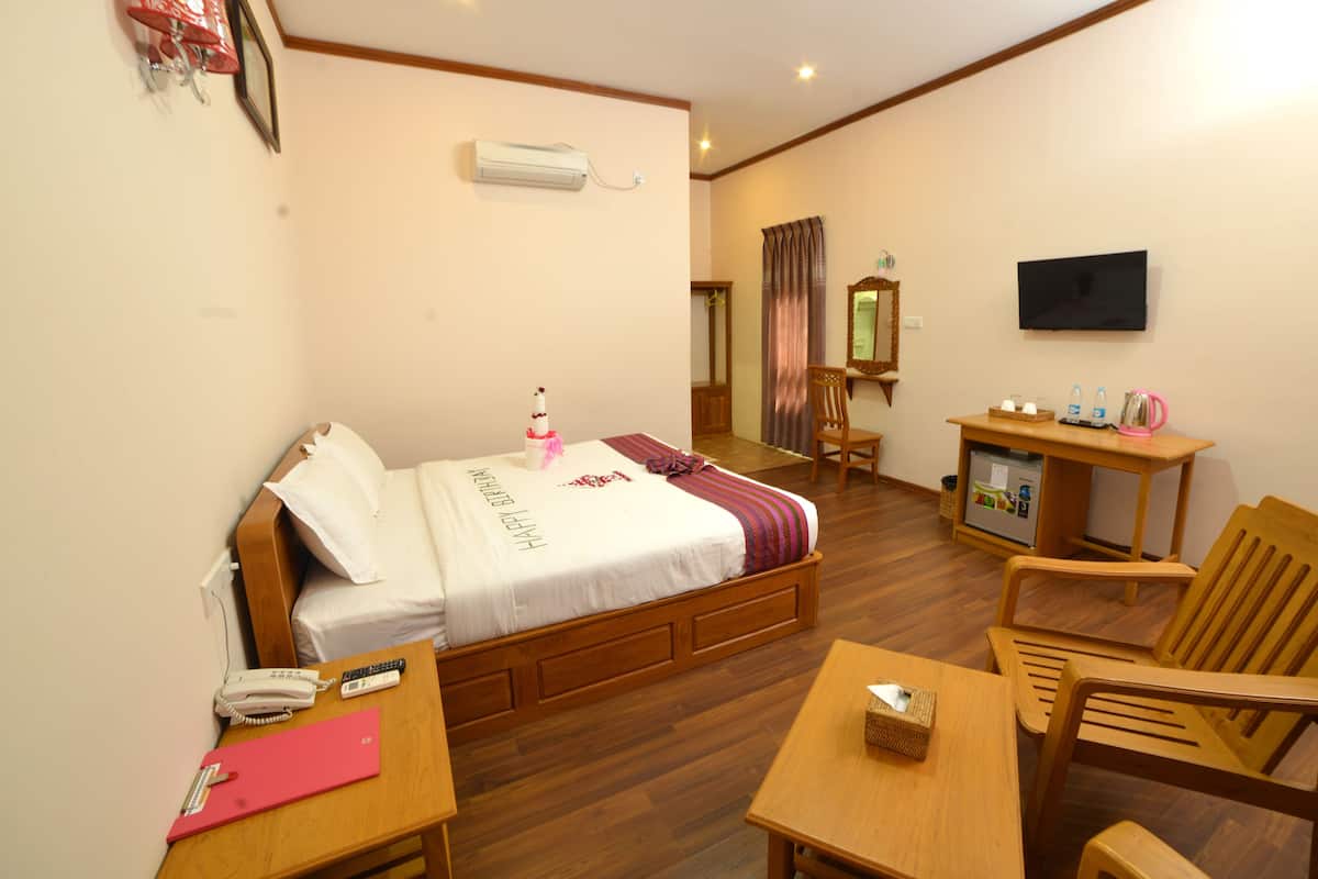 Habitación de hotel con cama, escritorio, silla, televisor y una pequeña cocina.