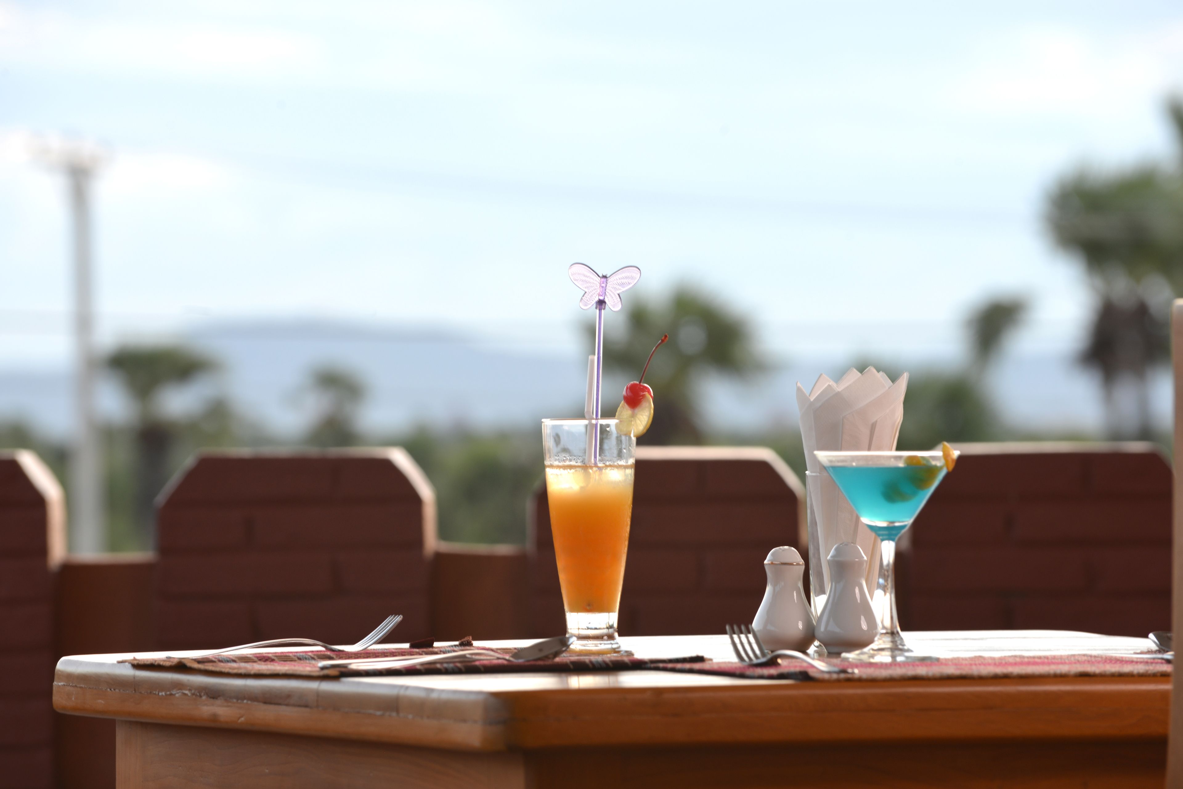 A table with two drinks, a fork, and a knife.