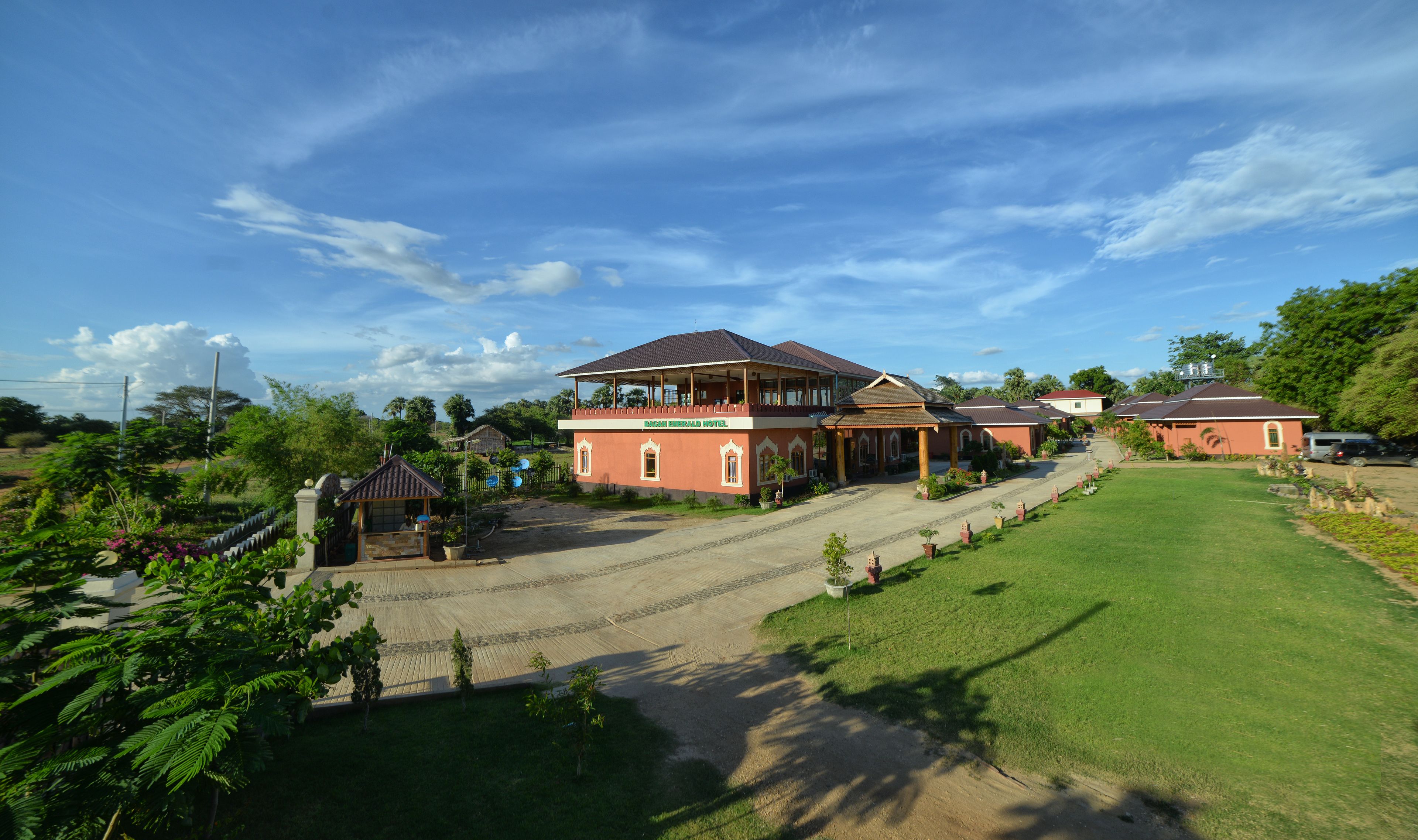 A large hotel with a covered outdoor area and a well-maintained lawn.