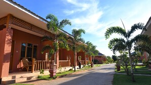 A residential street with houses, palm trees, and a clear sky.