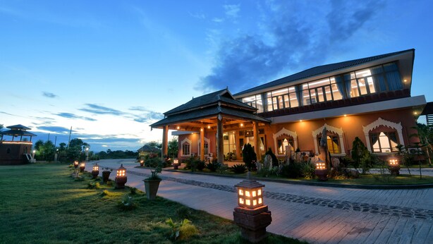 A modern hotel with a covered entrance, outdoor lighting, and a well-maintained garden.