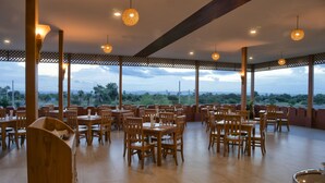 An open dining area with wooden tables and chairs, a wooden counter, and hanging lights.