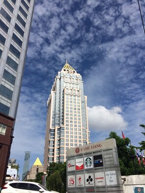 A tall building with a unique pyramid-shaped top and a sign indicating 'U CHU LIANG' with various logos.