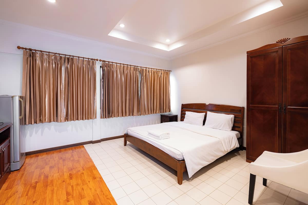 A bedroom with a wooden bed, a wardrobe, a nightstand, and a television.