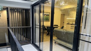 Um interior moderno com porta de vidro que dá para uma sala de jantar, um sofá e uma cozinha visível através do vidro.