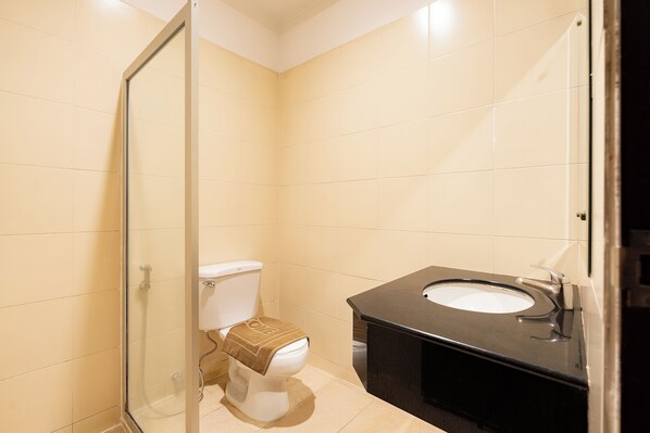 Un baño con inodoro, lavamanos y cabina de ducha de vidrio.