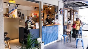 Um café com balcão revestido de azulejos azuis, banquetes e um letreiro que diz 'wide awake'.