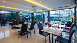 A modern hotel lobby with glass partitions, a mix of dining and seating areas, and large windows offering city views. - UDTEL Boutique Hotel (Udon Thani)