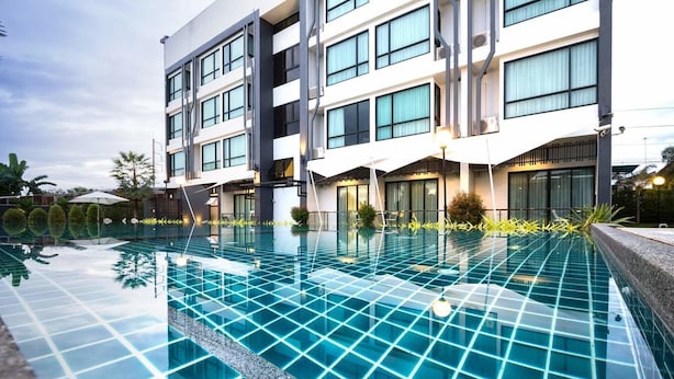 A modern hotel with a large swimming pool, multiple balconies, and a well-maintained garden area. - UDTEL Boutique Hotel (Udon Thani)