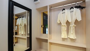 A hotel room with a large mirror, a walk-in closet with robes, and a small window. - UDTEL Boutique Hotel (Udon Thani)