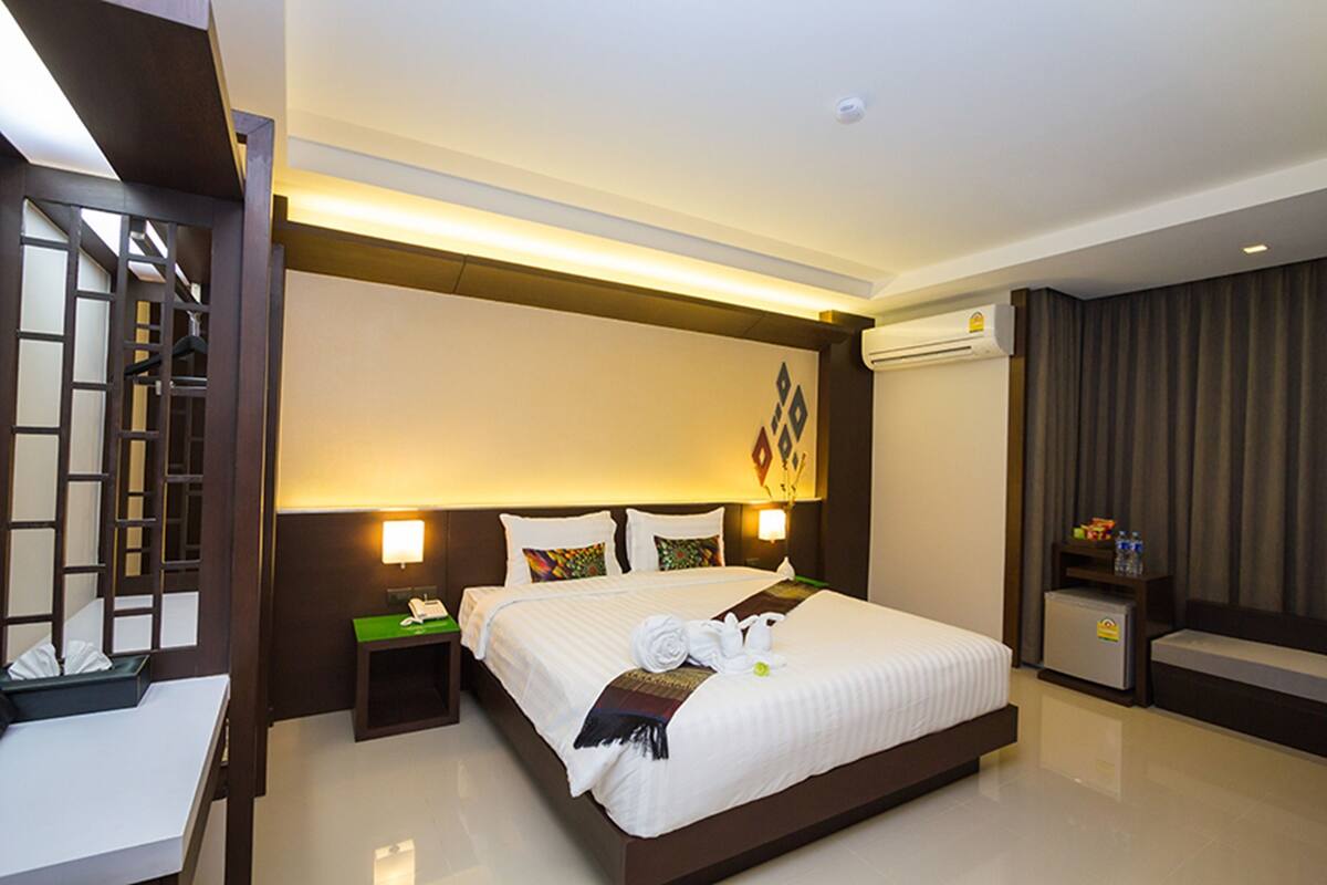 A hotel room with a large bed, bedside tables, a desk, and a chair.