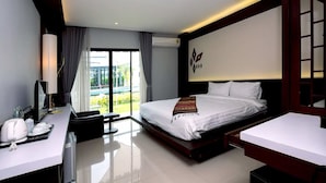 A modern hotel room with a large bed, a desk with a coffee maker, and a view of a pool. - UDTEL Boutique Hotel (Udon Thani)