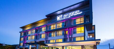 A modern hotel with a multi-story structure, large windows, and a prominent illuminated sign.