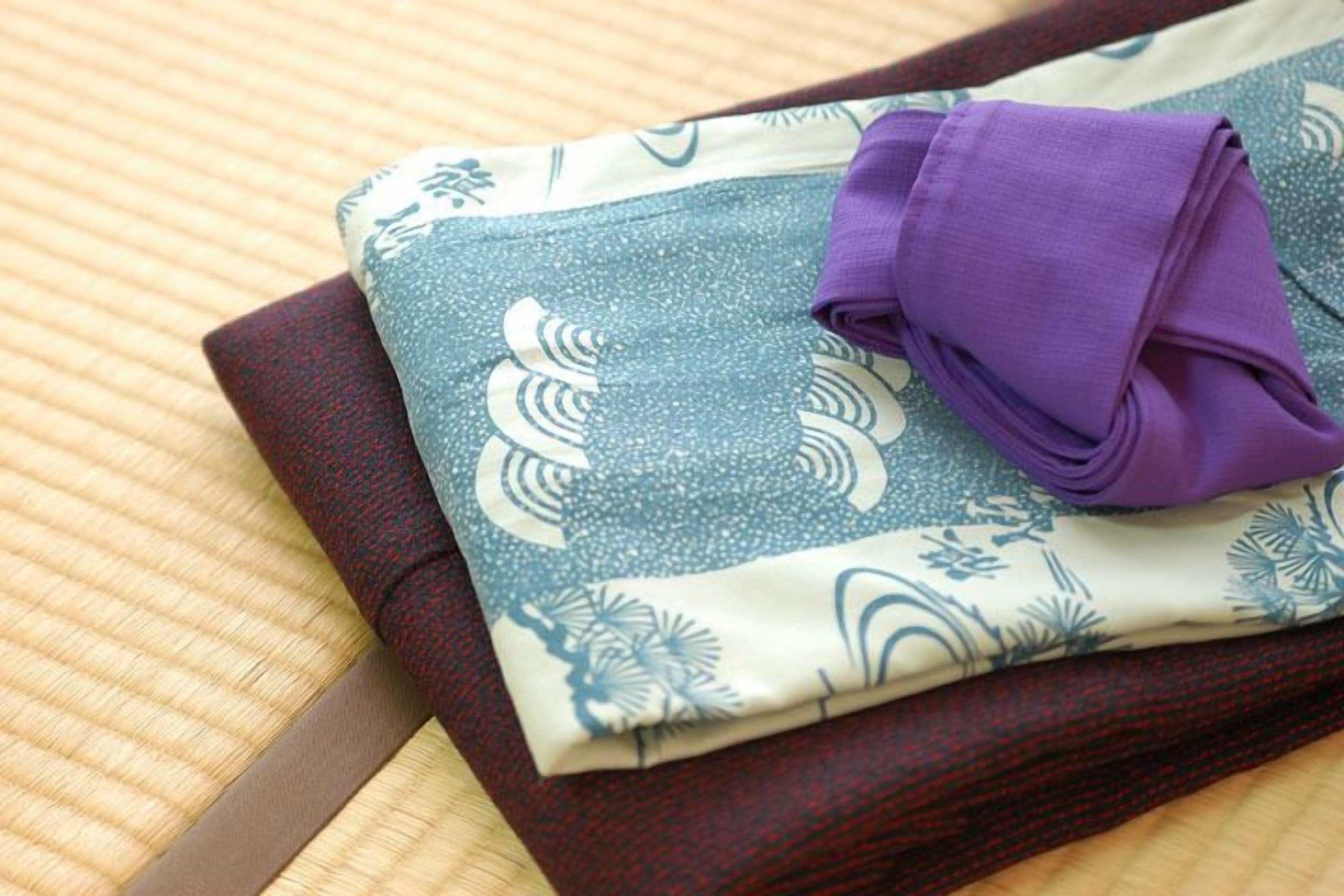 Un juego de ropa de cama doblada con un estampado azul y blanco, sobre una estera tejida.