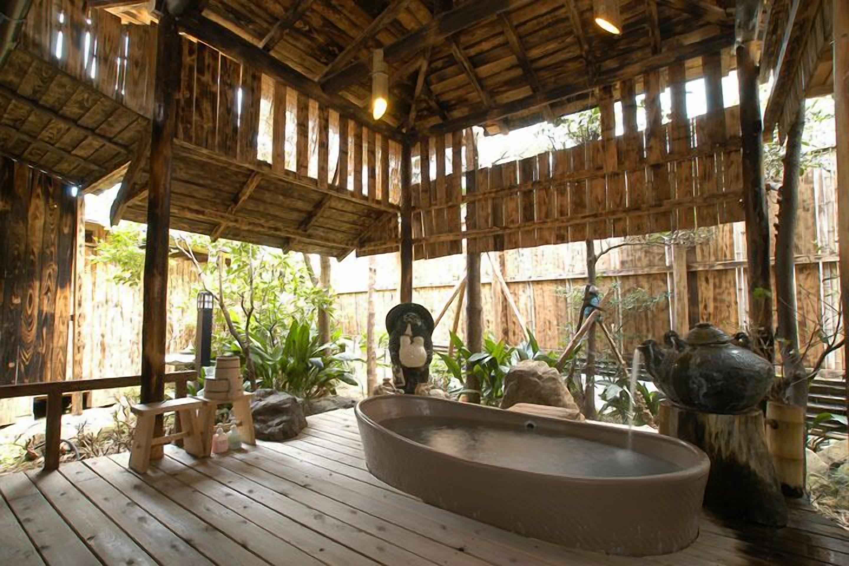 Une terrasse en bois avec un jacuzzi, entourée de plantes et agrémentée d’une décoration rustique.