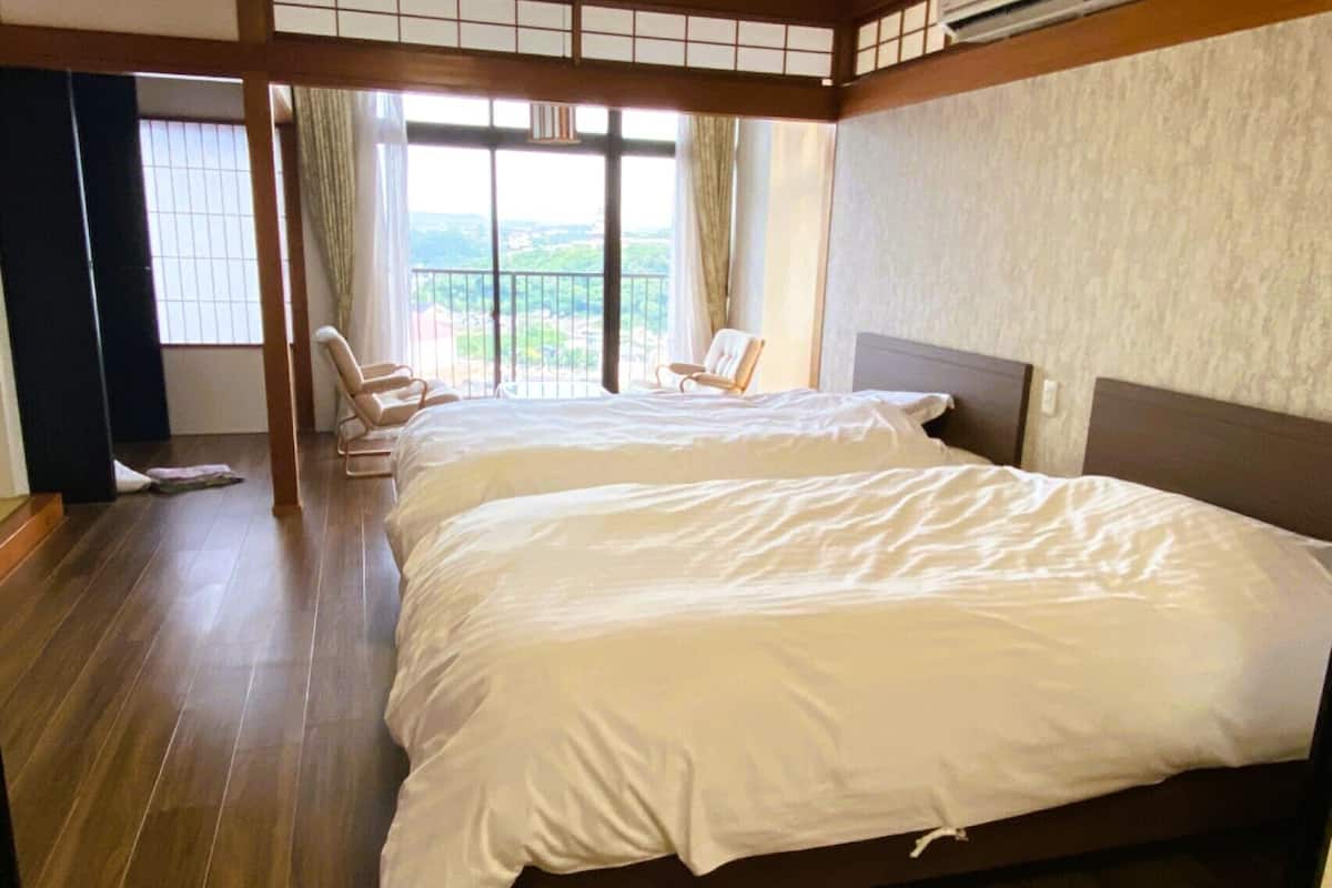 A hotel room with two beds, a balcony with a view, and a traditional Japanese-style interior.