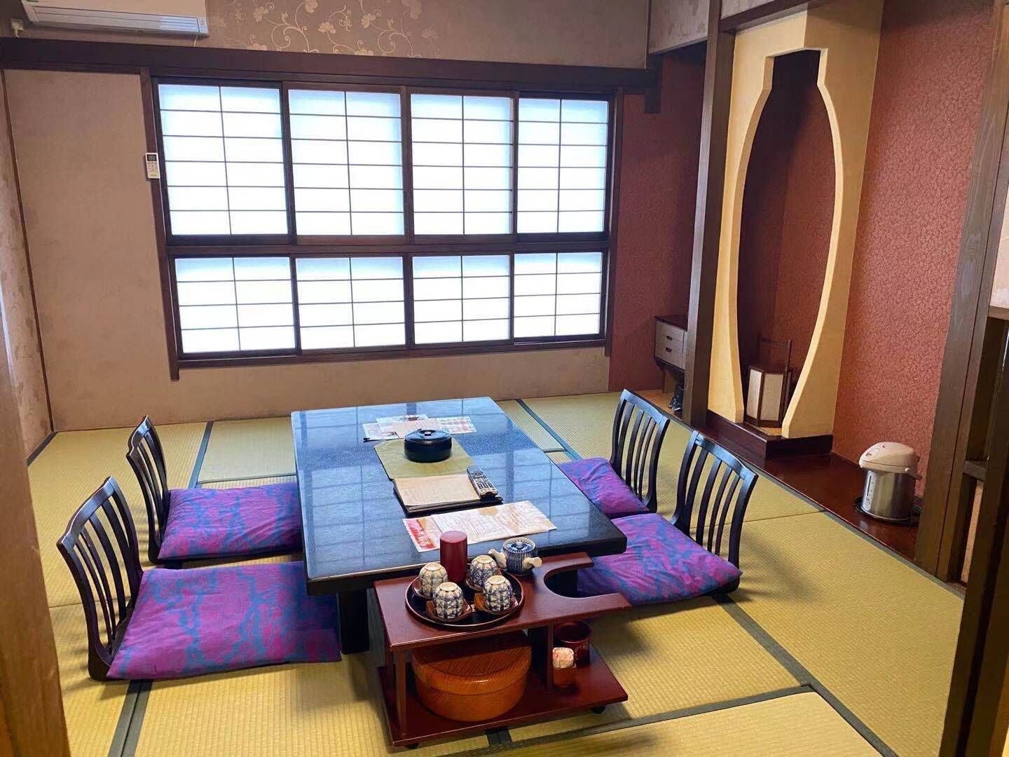 A tatami mat room with a low table, cushions, and a traditional Japanese tea set.