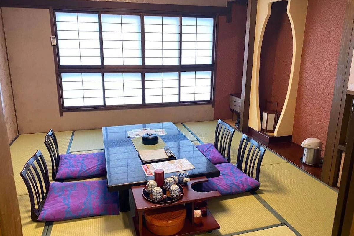 A tatami mat room with a low table, cushions, and a traditional Japanese tea set.
