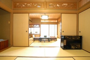 A traditional Japanese room with tatami flooring, a low table with cushions, and sliding doors. - Kokusai Kanko Hotel Kishotei (Hirado)