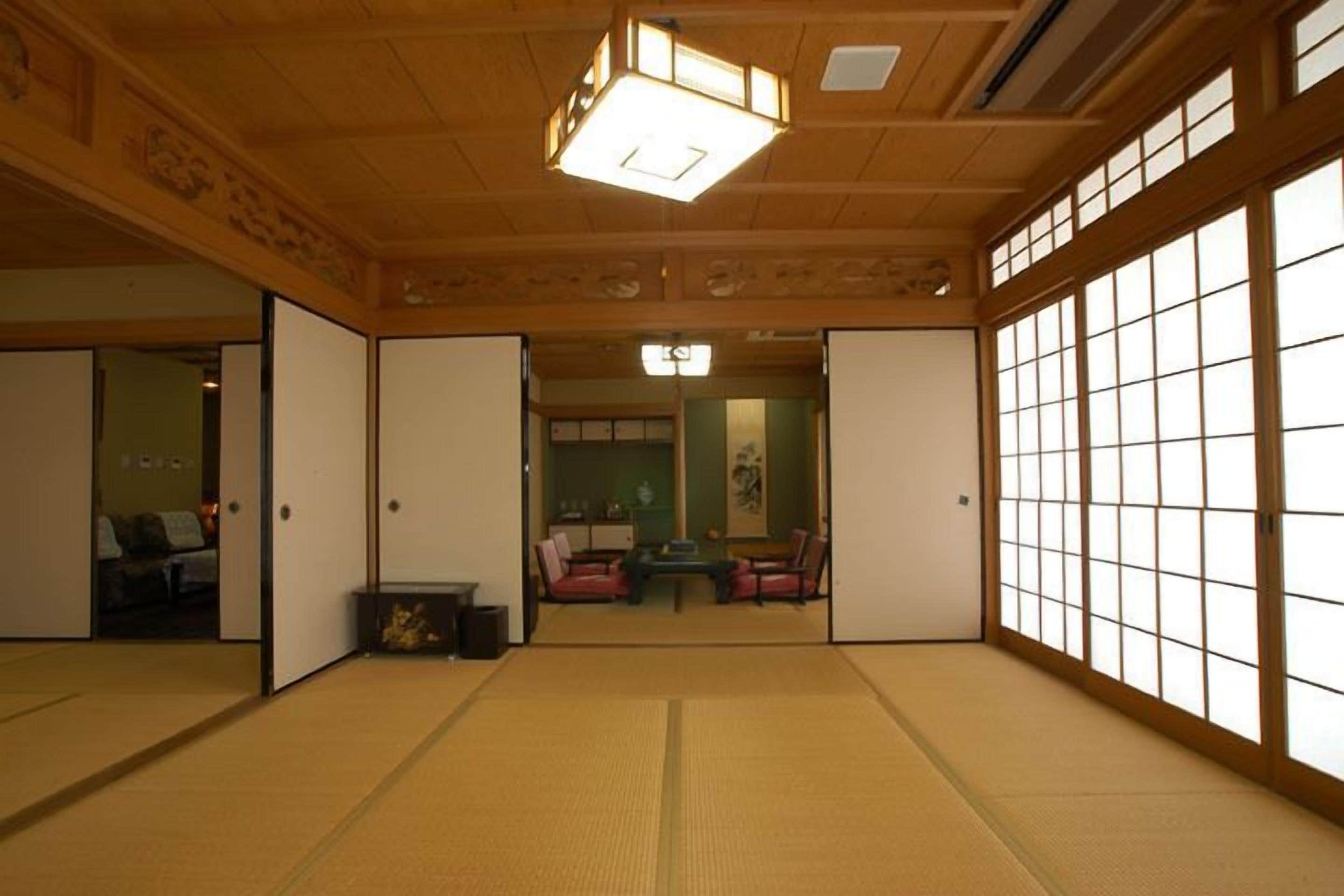 A traditional Japanese room with tatami flooring, sliding doors, and a view through a shoji screen.