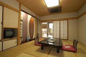 Um quarto japonês tradicional com tatames, uma mesa baixa e portas deslizantes shoji.