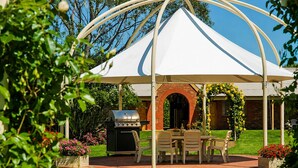 A covered patio area with a grill, dining table, and chairs. - Coonawarra Place Motor Inn (Coonawarra)