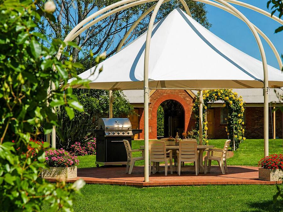 A covered patio area with a grill, dining table, and chairs.