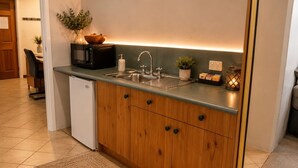 A compact kitchen with a built-in microwave, a sink, and wooden cabinets. - Coonawarra Place Motor Inn (Coonawarra)
