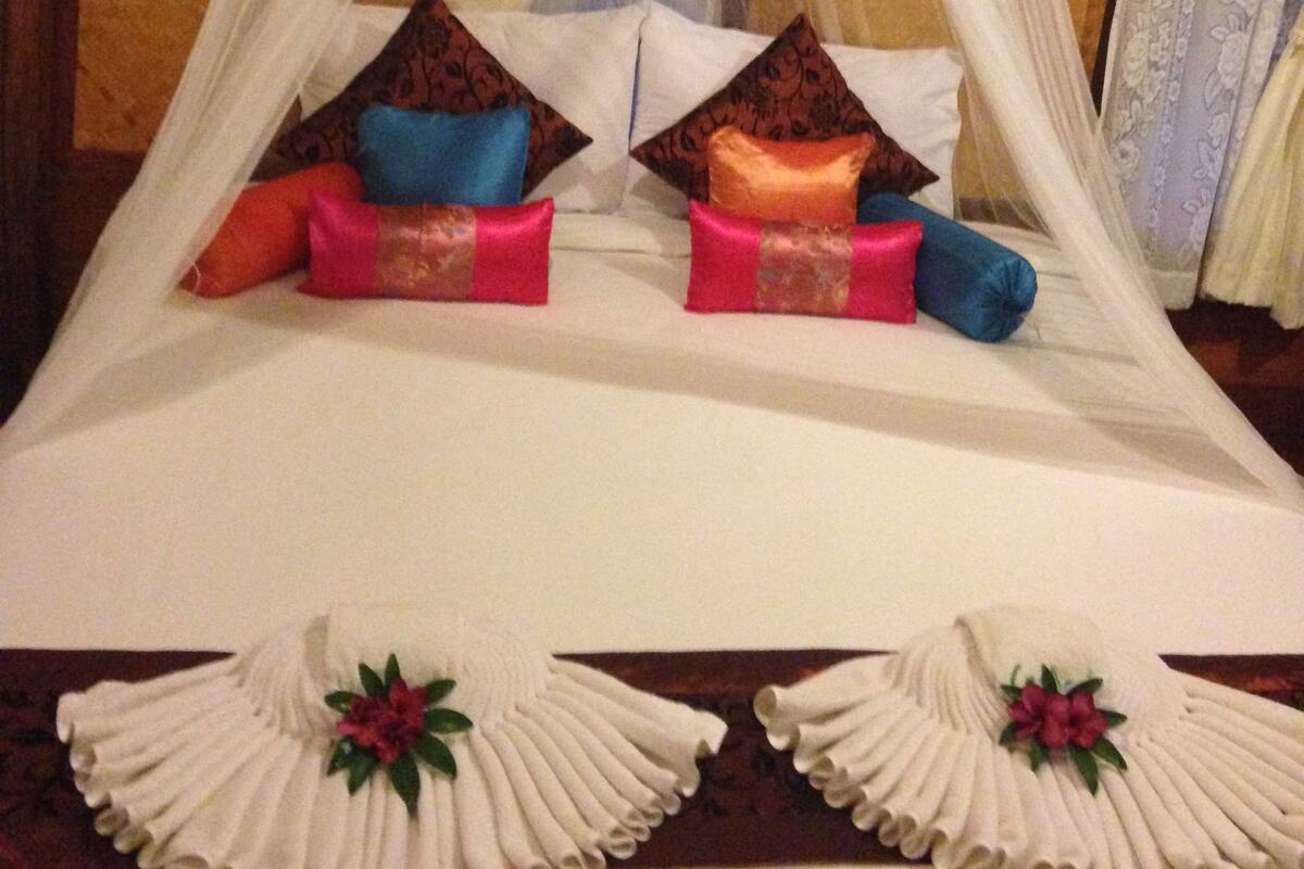 A bed with a canopy, pillows, and decorative pillows.
