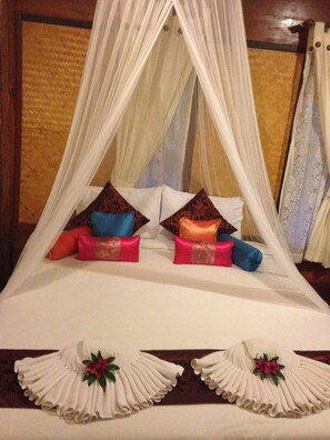 Uma cama com dossel, almofadas e travesseiros decorativos.
