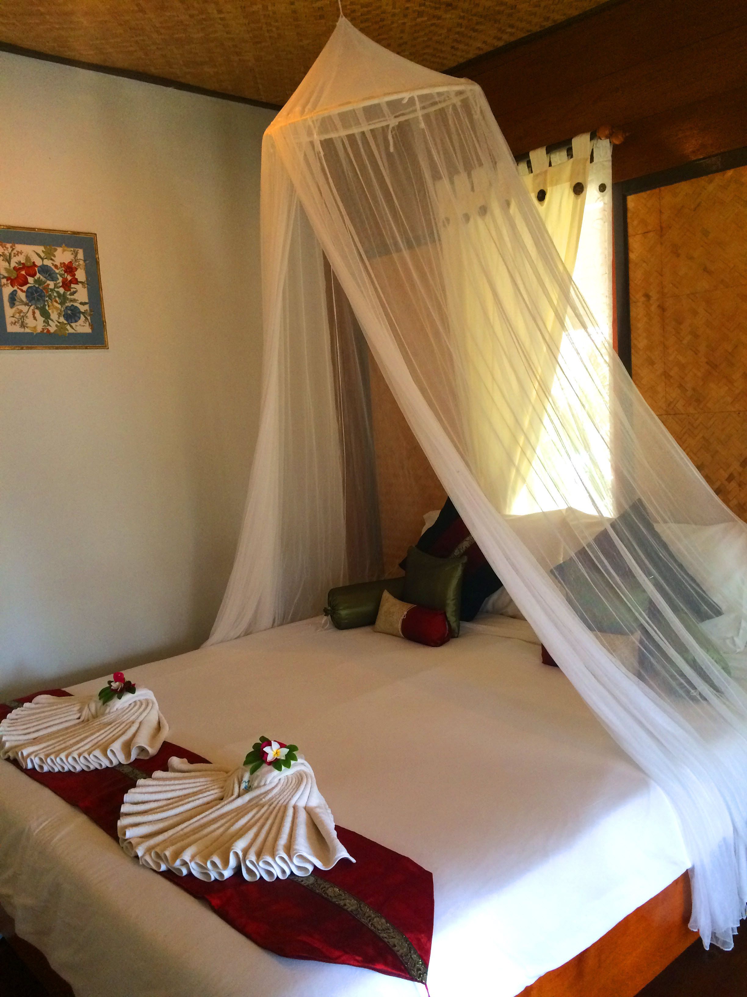 Un lit à baldaquin, avec des oreillers et une disposition décorative des serviettes.