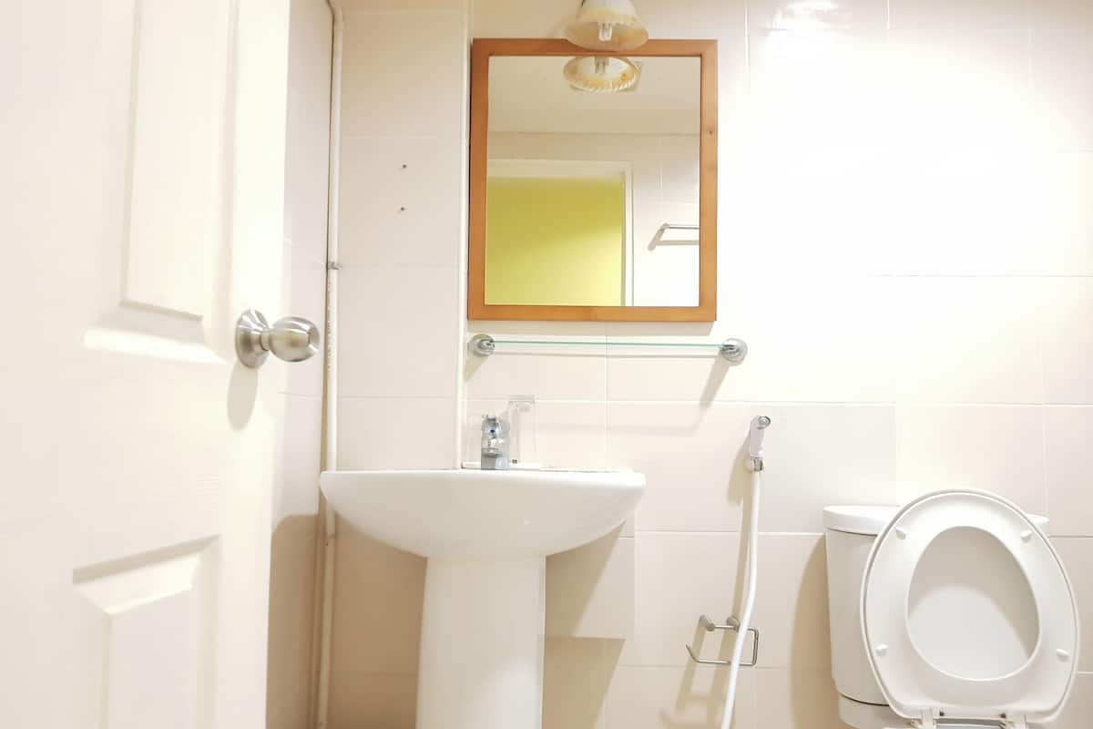 A bathroom with a white sink, a mirror, and a toilet.