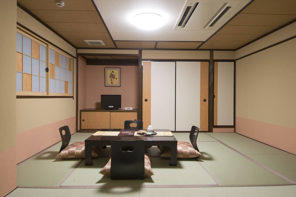 Ein traditioneller japanischer Raum mit Tatami-Böden, einem niedrigen Tisch und Kissen.