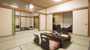 Ein traditioneller japanischer Raum mit Tatami-Böden, einem niedrigen Tisch und schwarzen Stühlen.