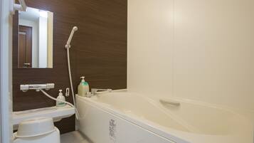 A modern bathroom with a bathtub, a sink, a mirror, and a shower head.