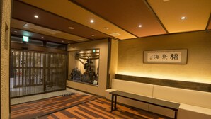 Ein Empfangsbereich mit Holzboden, einer Bank und einem an der Wand befestigten Schild mit japanischen Schriftzeichen.