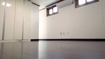 A spacious room with a polished floor, a large window, and a wall-mounted air conditioning unit.